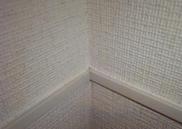 「幕板見切６Ｔ」は、上下２つの部材が上下左右に動いてクロスのシワを防ぐ。見付巾は６.２ミリ。１４８０円／本（２.７ｍ）