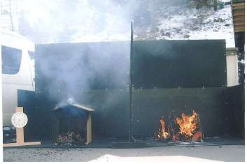 燃焼実験で、着火２０分後の様子。写真左側は不燃処理済みの材。右側の未処理材は着火後５分で開口上部の横桟が割れ、１２分で屋根が落ち、１５ 分でほぼ全焼した