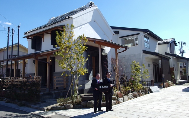 贈呈された土蔵の前で記念撮影に応える高橋努越谷市長（左）と品川典久中央住宅社長